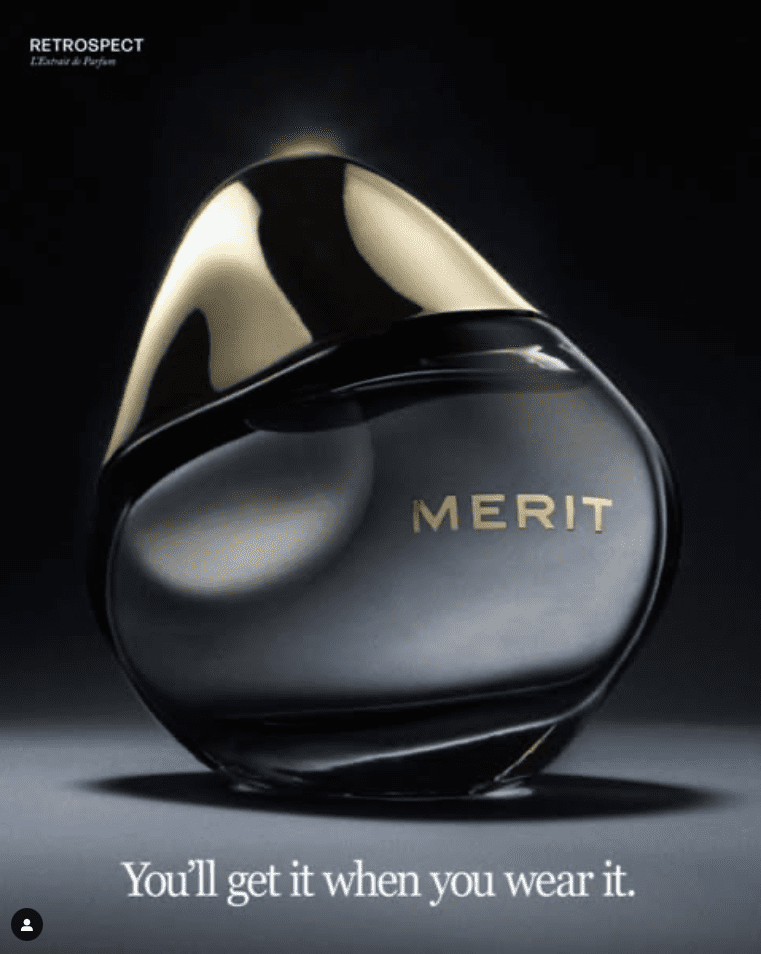 A rounded black MERIT fragrance bottle with a curved gold cap against a dark background.
